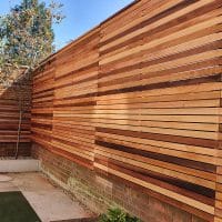 here we have a cedar slat fence with 7mm gaps. it has been cleverly fitted alongth edge of a brick wall.