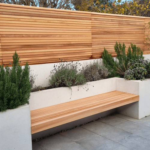 A Cedar floating garden bench beside a matching Cedar fence panel, also by Contemporary Fencing.