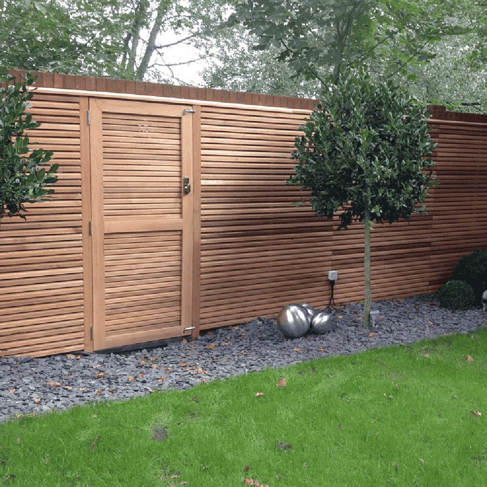 A contemporary fence design made of Canadian Red cedar with a gravel path below it. Made in the UK.