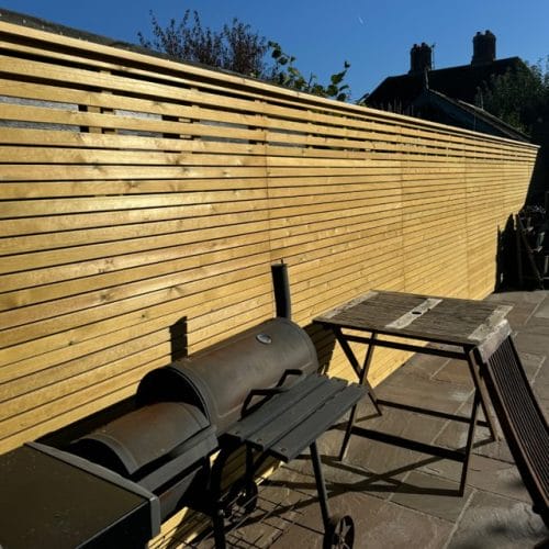 A horizontal slat fencing.in a sunny garden.