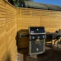 Horizontal slatted fencing panels create a a backdrop for a BBQ area