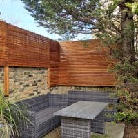 New Venetian slatted fence panels installed on top of a brick wall